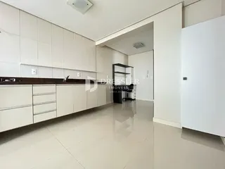 Interior de uma sala de estar com armários brancos e piso claro.