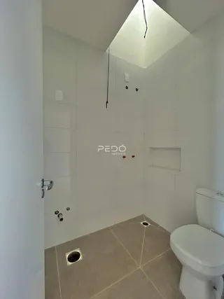Foto interna de um banheiro com revestimento cerâmico e piso claro.