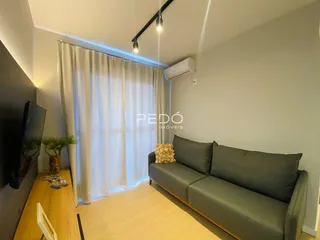 Sala de estar com sofá e janela iluminada.