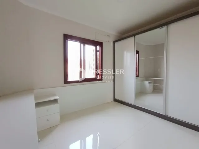 Sala de estar clara com janela e armário branco.