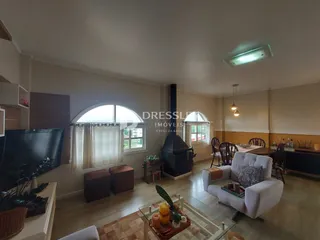 Sala de estar com janelas arqueadas e lareira em um imóvel no Brasil.