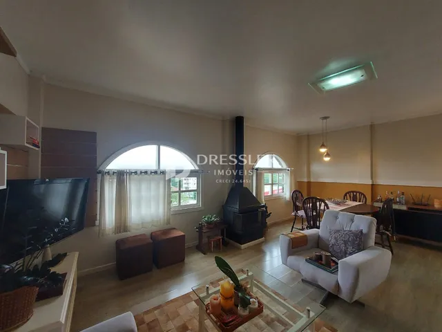 Sala de estar com janelas arqueadas e lareira em um imóvel no Brasil.