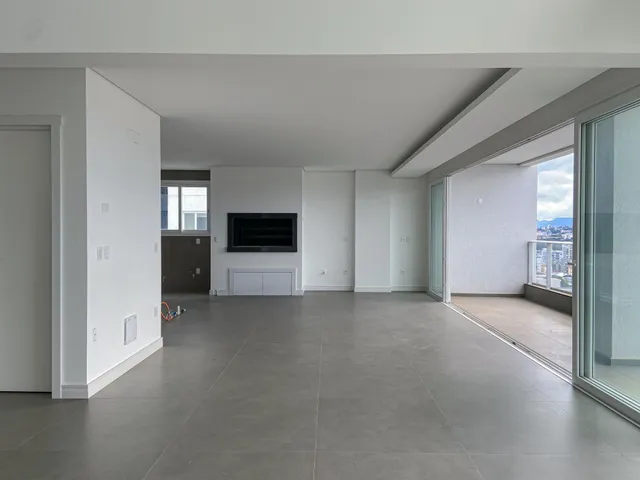 Sala ampla com piso de porcelanato cinza e vista da cidade através da porta de vidro.