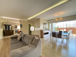 Sala de estar com sofá grande e piso de madeira, com acesso a uma área externa.