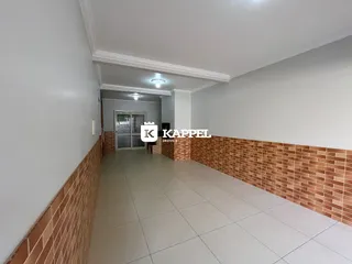 Foto de um corredor interno com paredes brancas e detalhes em tijolo aparente.