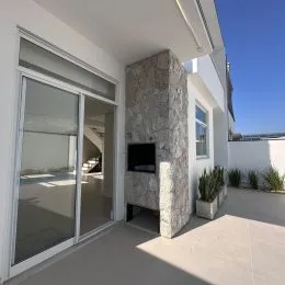 Vista da fachada de uma residência com porta de vidro e coluna de pedra.