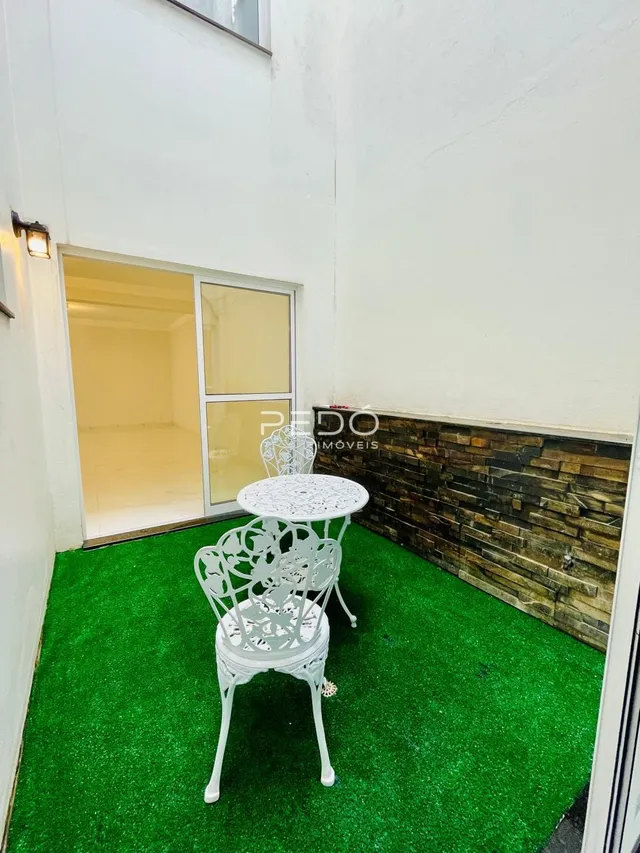 Interior de uma sala com piso verde artificial e mesa decorativa.
