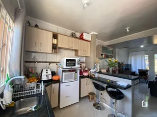 Foto de uma cozinha com armários brancos e bancada escura.