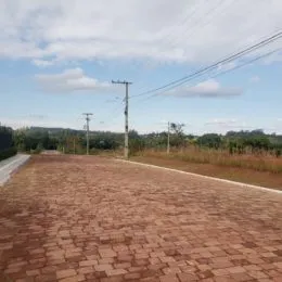 Vista de uma área pavimentada com vegetação ao fundo.