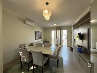 Sala de estar com mesa de jantar e cortinas em um imóvel no Brasil.