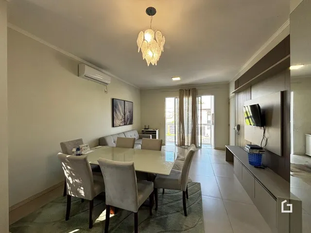 Sala de estar com mesa de jantar e cortinas em um imóvel no Brasil.