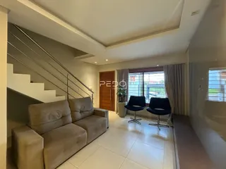 Sala de estar com sofá e escadaria em um apartamento no Brasil.