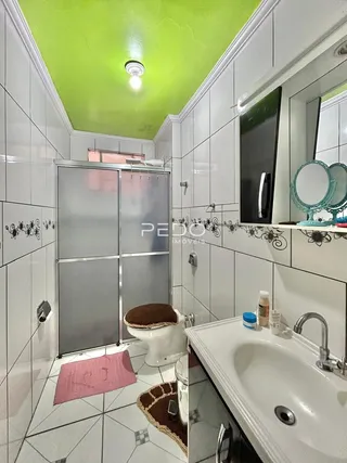 Foto de um banheiro com revestimento branco e piso de cerâmica.