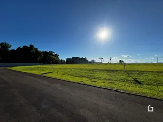 Vista de um campo gramado com uma estrada no primeiro plano.
