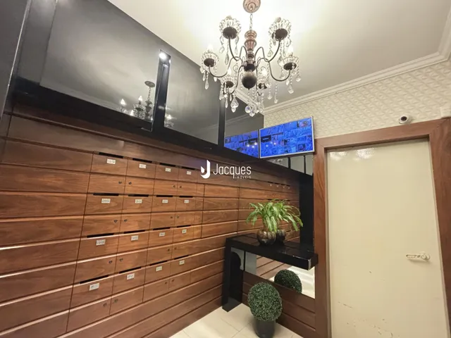 Sala de estar com painel de madeira escura e lustre de cristal.