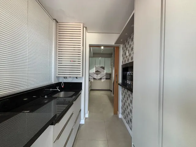Vista da cozinha com armários brancos e bancada escura em Lajeado.