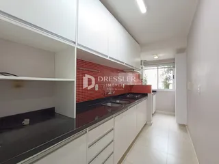 Vista interna de uma cozinha com armários brancos e revestimento vermelho.