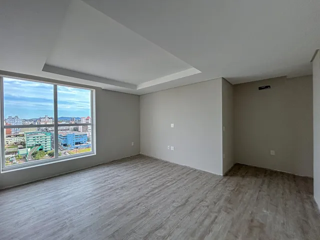 Sala de estar ampla com grande janela oferecendo vista da paisagem urbana.