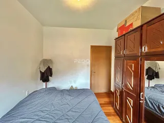 Quarto com cama e armário de madeira em ambiente claro.