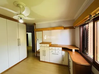 Interior de uma sala com armários brancos e piso de madeira clara.