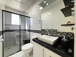 Banheiro moderno com box de vidro e revestimento de azulejos.