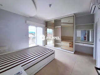 Quarto com cama de madeira e armário embutido em um apartamento em Lajeado.