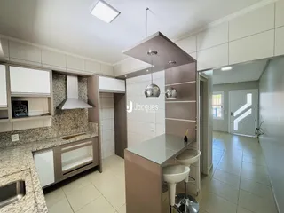 Cozinha moderna com ilha e armários brancos em um imóvel no Brasil.