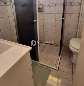 Foto de um banheiro com paredes de azulejo branco.