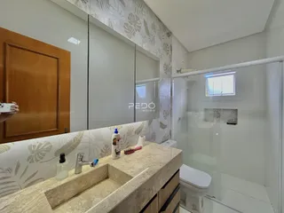 Banheiro moderno com box de vidro e bancada de granito.
