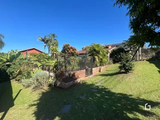Jardim gramado com cerca de tijolos e vegetação ao ar livre.