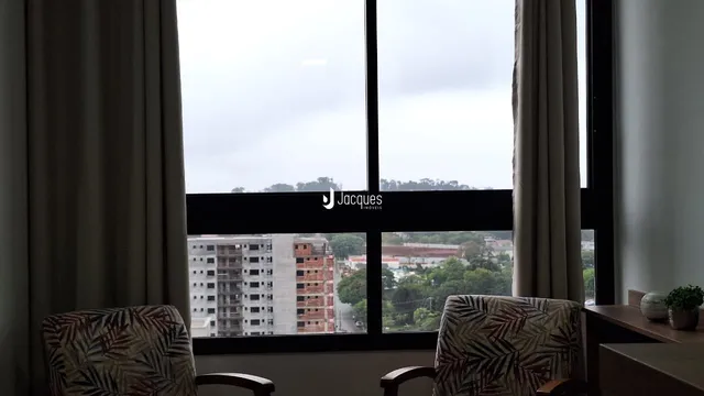 Vista da janela de um imóvel em Lajeado, Brasil, com cortinas e móveis no primeiro plano.
