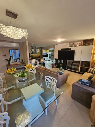 Sala de estar com mesa de vidro e móveis de madeira clara.