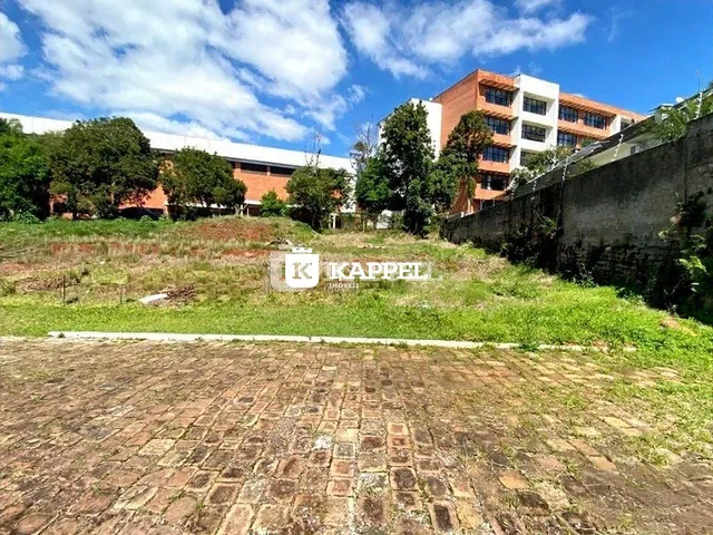 Vista externa de uma propriedade com muro de concreto e área de terra.