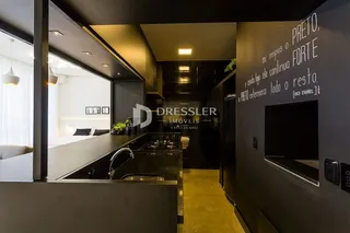 Interior de uma cozinha moderna com armários escuros e bancadas.
