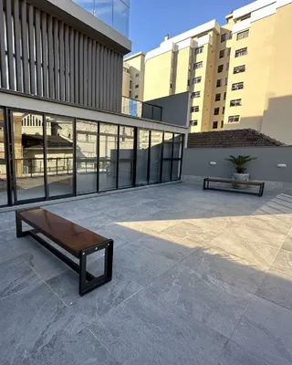 Área externa com piso de concreto e banco de madeira.