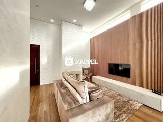Sala de estar com sofá grande e televisão em ambiente moderno.