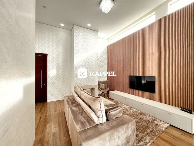 Sala de estar com sofá grande e televisão em ambiente moderno.