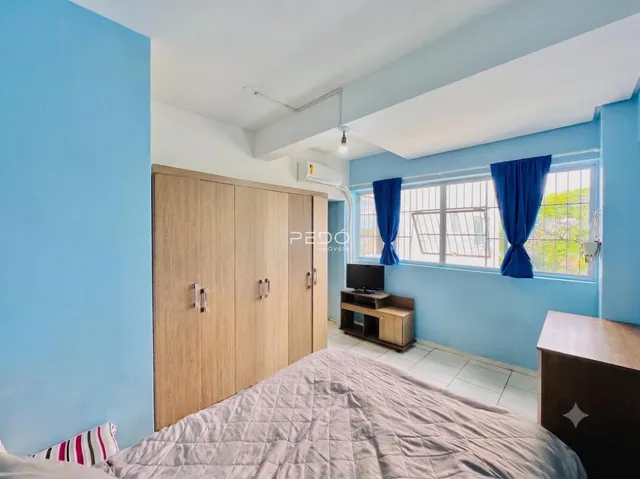 Quarto com armário de madeira e janela azul em um imóvel no Brasil.