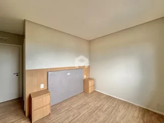 Interior de uma sala com paredes brancas e piso de madeira clara.
