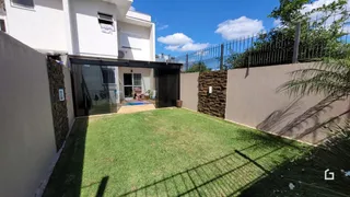 Vista externa de uma residência com jardim gramado e muro de pedra.