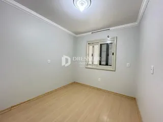 Foto de um cômodo interno com paredes brancas e piso de madeira clara.