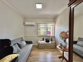 Sala de estar com sofá cinza e piso de madeira clara.