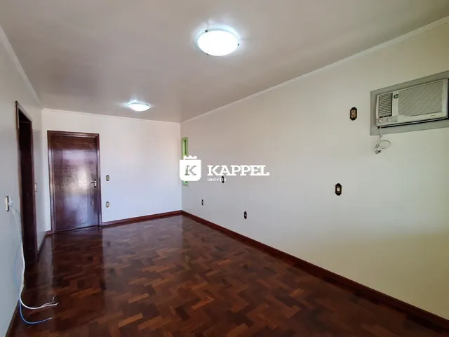 Sala de estar com piso de madeira escura e ar condicionado instalado na parede.