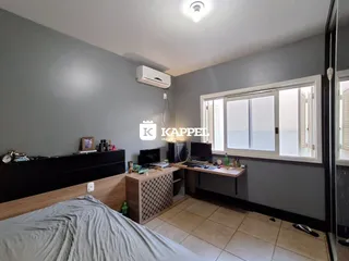 Quarto com cama e armário escuro em ambiente com piso de cerâmica.