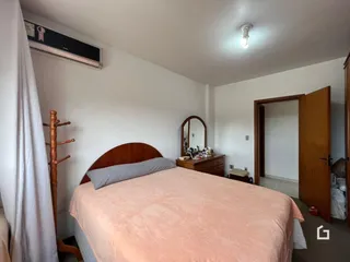 Quarto com cama de madeira e cortina branca na sala.