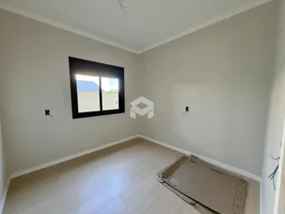 Ambiente interno de uma sala com piso de madeira clara e parede branca.