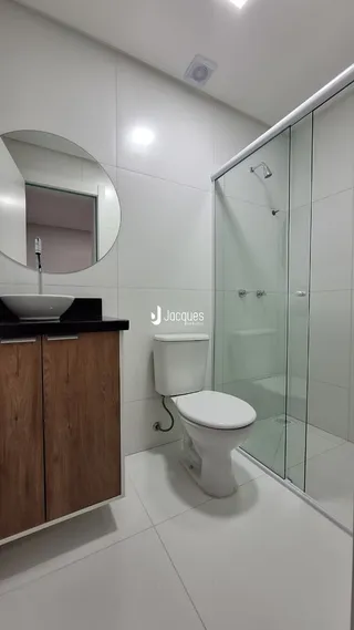Banheiro moderno com box de vidro e revestimento branco.