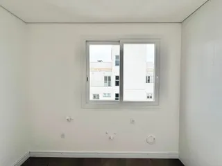 Foto de um cômodo interno com parede branca e uma janela.