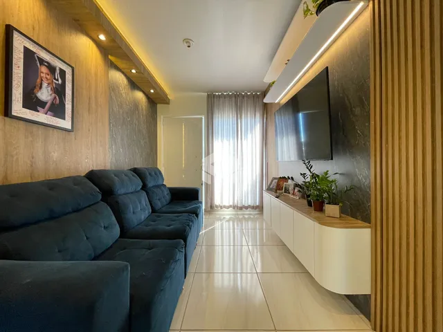 Sala de estar com sofás azuis e piso claro em um imóvel no Brasil.