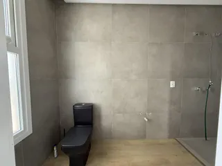 Foto de um banheiro com revestimento de azulejos cinza e piso de madeira clara.